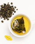 Timebai Pomelo Oolong Tea Brewing in a White Cup Beside Loose Tea Leaves