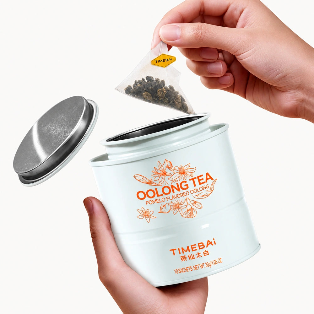 Timebai Pomelo Oolong Tea – Hand Lifting a Pyramid Tea Bag from an Open Tin