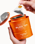 Timebai Ceylon Black Tea – Hand Lifting a Pyramid Tea Bag from an Open Tin